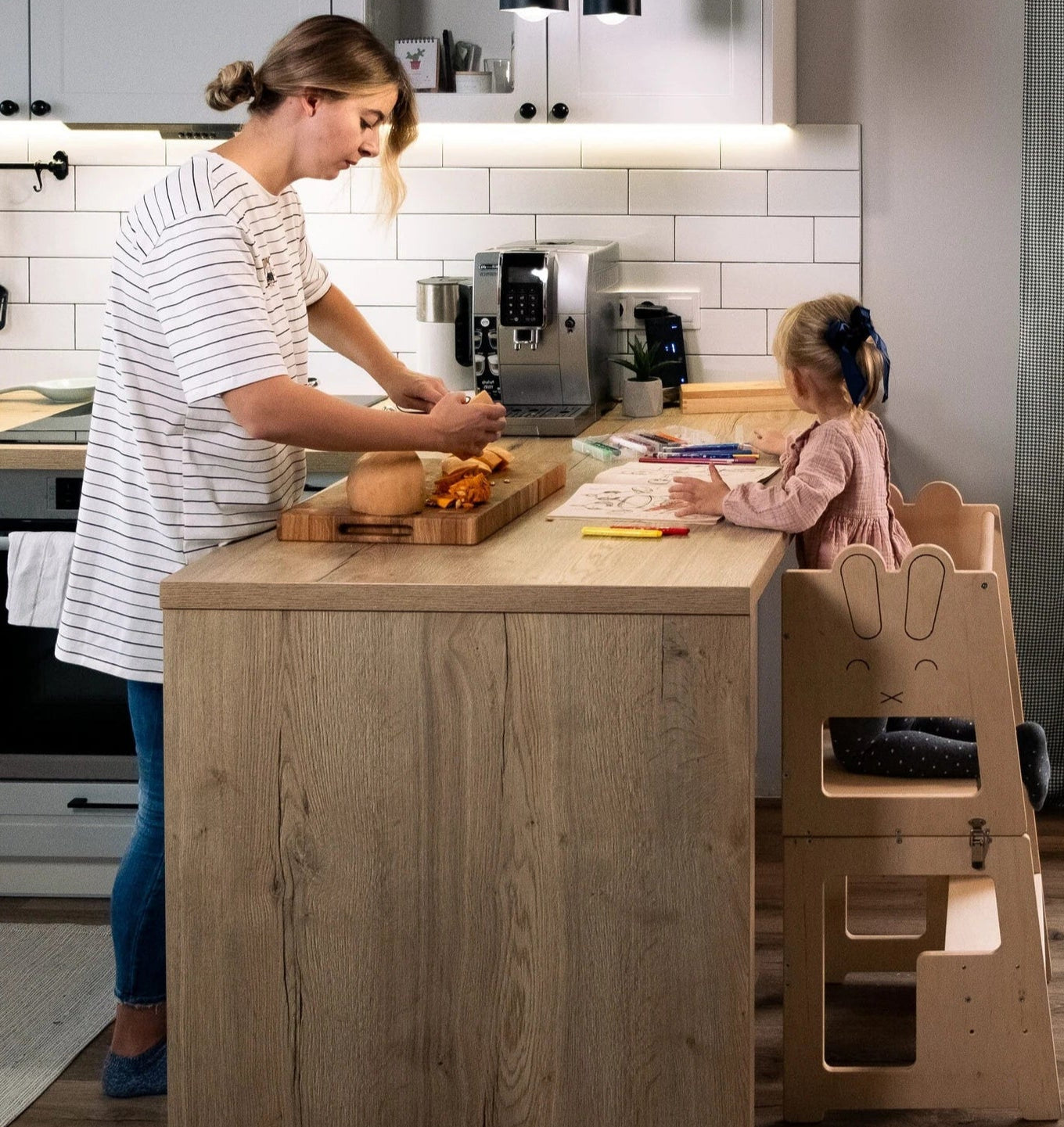 Woman and child in a kitchen with a wooden step stool.