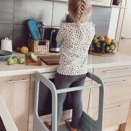 Child using non-foldable wooden Learning Tower, participating in kitchen activities