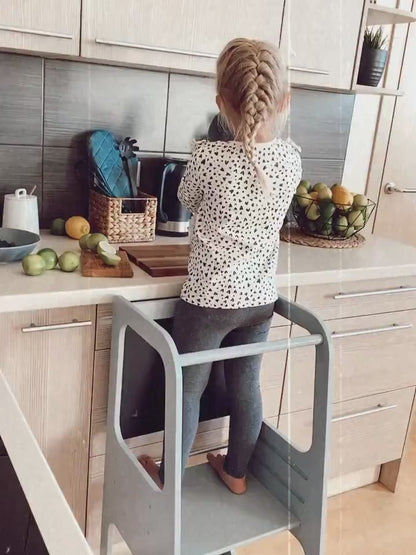 Child using non-foldable wooden Learning Tower, participating in kitchen activities